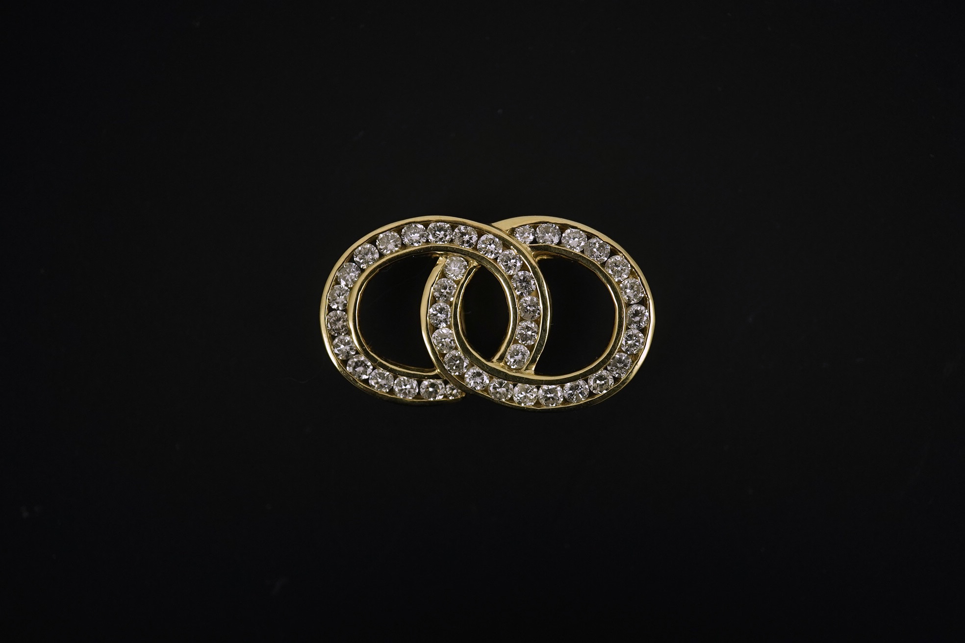 A modern 14k gold and diamond cluster set interwoven double loop pendant